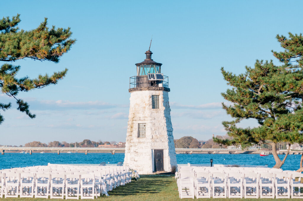 Peaceful waterfront ceremony setup at Newport Harbor Island Resort featuring rows of white chairs and the Goat Island lighthouse before guests arrive.