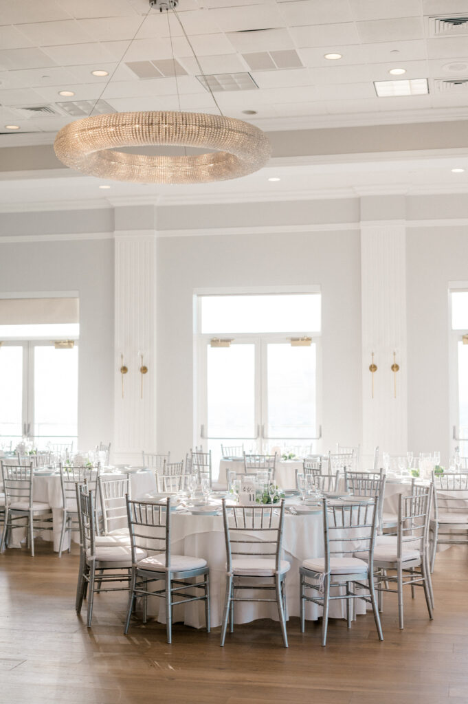 Reception room at Newport Harbor Island Resort with round tables, silver chairs, and soft coastal lighting.