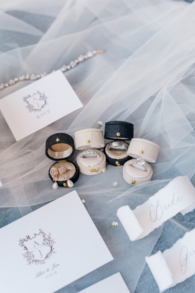Flatlay of velvet ring boxes, pearl earrings, and monogrammed stationery for coastal Newport wedding details