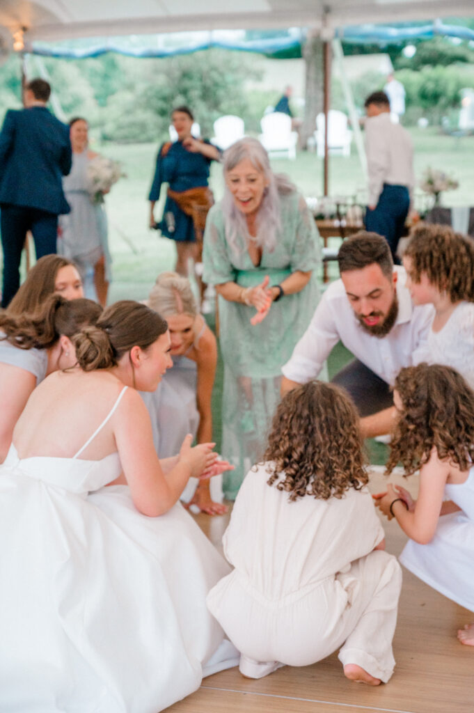 Bride playing clapping games with children on the dance floor, showcasing candid moments during a Connecticut wedding photography timeline documented by Jennifer Nichole.