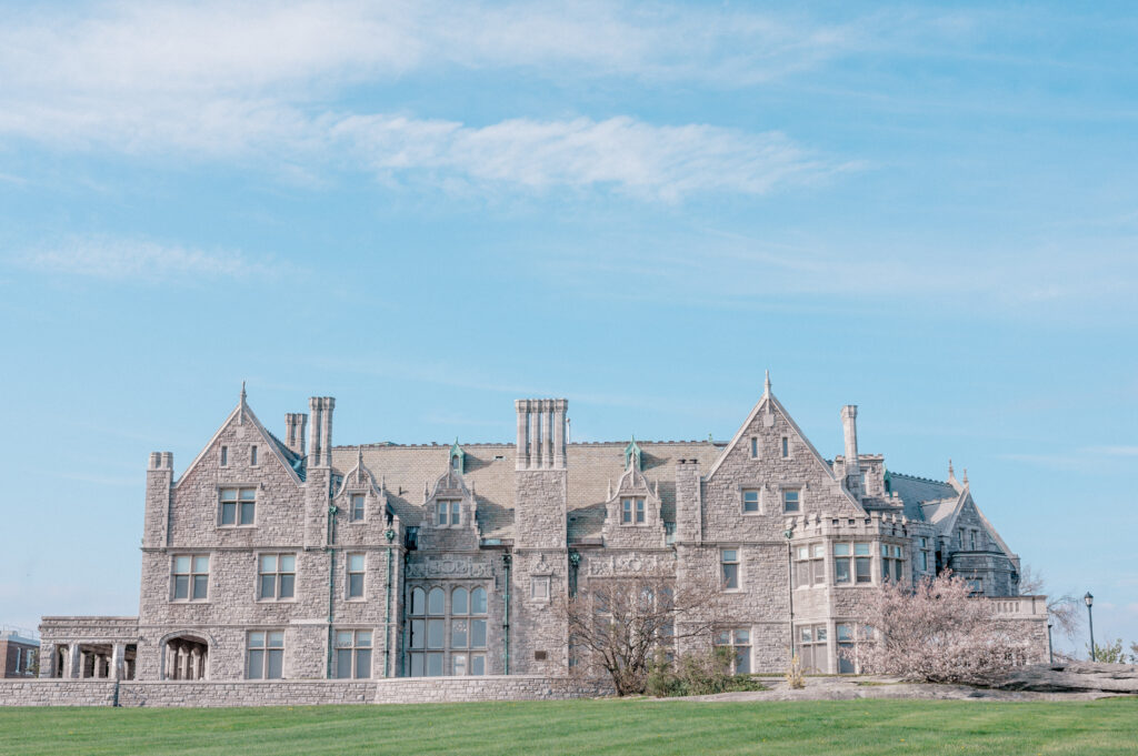Elegant side facade of Branford House Mansion surrounded by soft spring cherry blossoms and green lawn