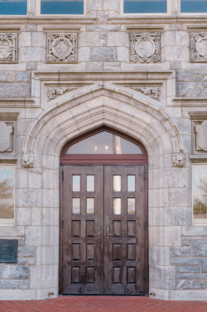 Ornate stone arch framing the main entrance doors at Branford House wedding venue in Groton, Connecticut
