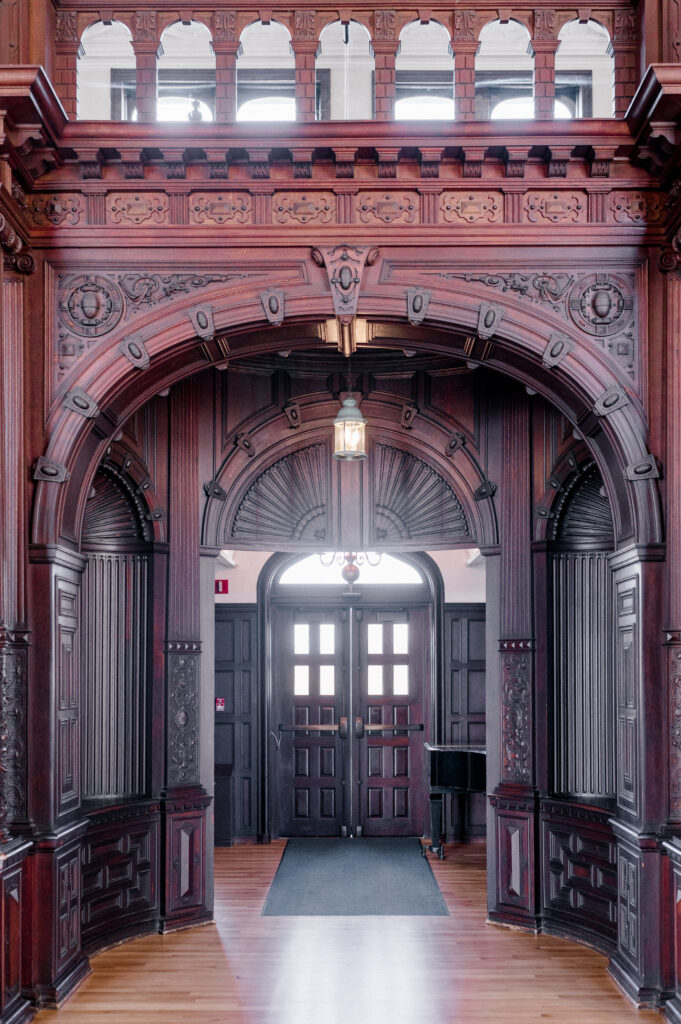 Gothic-style entry hall with carved wood arch and upper gallery at Branford House Mansion, perfect for heirloom wedding photos