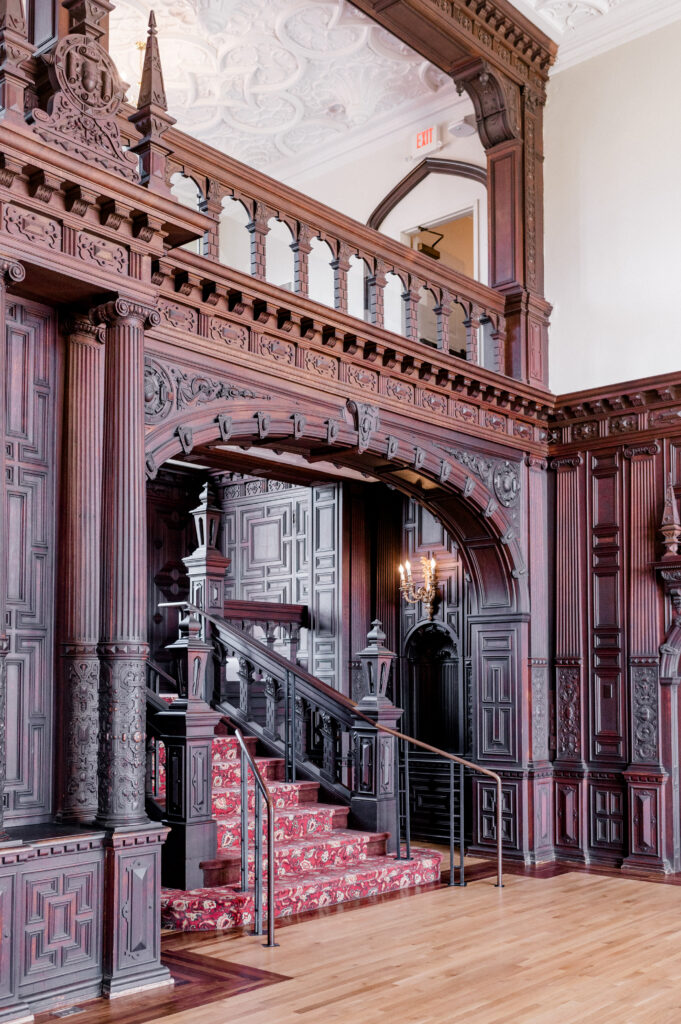 Interior staircase with red runner and carved woodwork inside Branford House Connecticut wedding venue