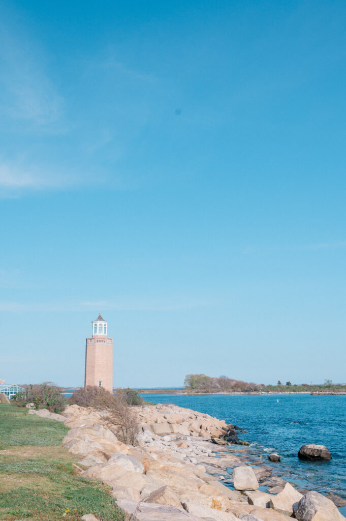 Brick lighthouse near Branford House wedding venue with coastal rocks and deep blue water