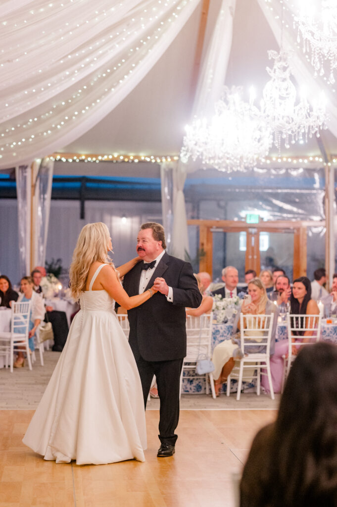 Bride sharing a joyful father-daughter dance beneath chandeliers and draped tent ceiling, captured as part of a Newport wedding by Jennifer Nichole.