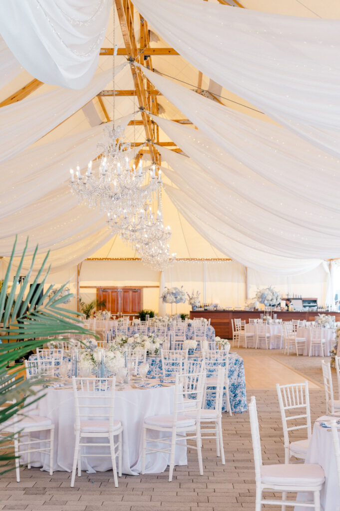 Romantic sailcloth tent reception with chandeliers and blue-and-white floral linens, part of a Newport wedding by Jennifer Nichole & Co.