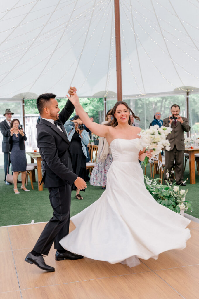 Bride and groom share a joyful first dance under a sailcloth tent at Smith Farm Gardens, captured in romantic wedding photography.