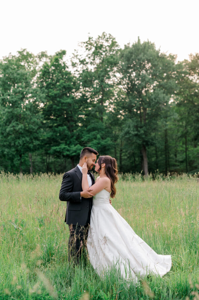 Bride and groom embracing in a lush green field at Smith Farm Gardens during golden hour.