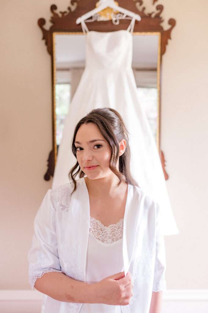 Bride smiling while seated in robe during hair and makeup at a romantic Smith Farm Gardens wedding