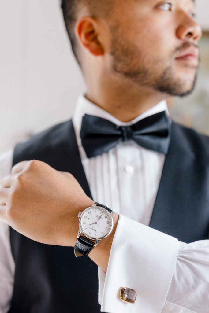 Groom adjusting his cufflinks in black tuxedo on the morning of his Smith Farm Gardens wedding