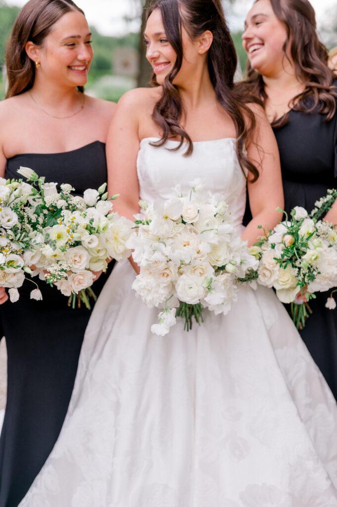 Close-up of the bride and bridesmaids smiling with lush white floral bouquets at Smith Farm Gardens.