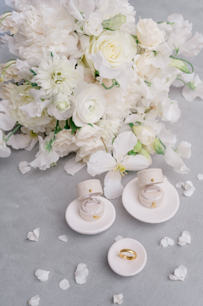 Flatlay of elegant white floral arrangement, vow books, and wedding invitation suite at a Smith Farm Gardens wedding