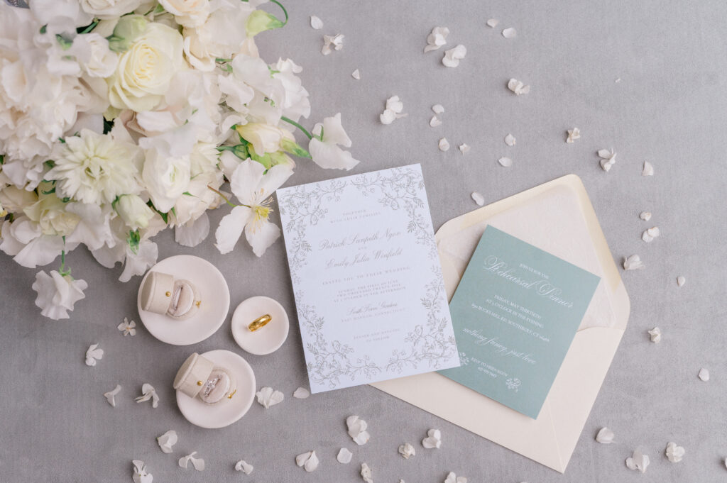 Elegant wedding invitation suite styled with white florals and velvet ring boxes, photographed at Smith Farm Gardens in Connecticut.