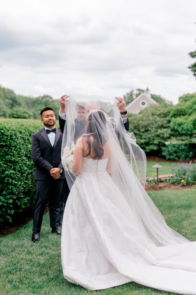 The bride’s father lifts her veil as she meets Patrick at the altar at Smith Farm Gardens