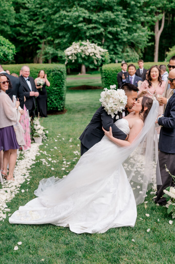 Just married! Patrick dips Emily for a joyful kiss down the petal-strewn aisle at Smith Farm Gardens
