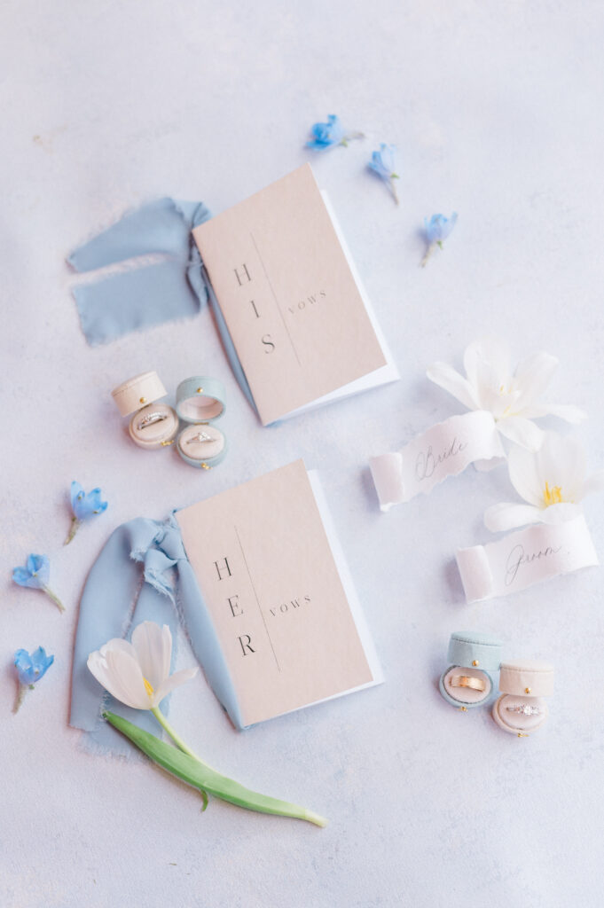 His and hers vow books in neutral tones styled with blue florals for a coastal Newport wedding, heirloom flat lay by Jennifer Nichole & Co.
