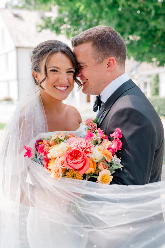 Close-up of joyful bride and groom with colorful summer bouquet at Smith Farm Gardens, photographed by heirloom wedding photographer Jennifer Nichole.