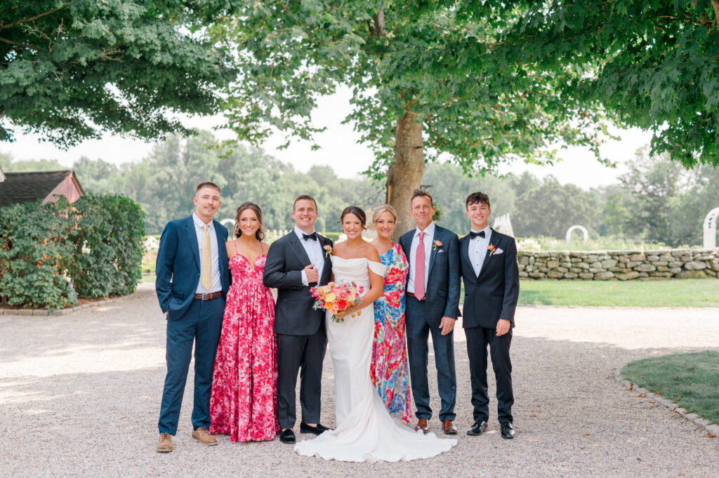 Bride and groom with family members smiling beneath trees during joyful Smith Farm Gardens wedding portraits